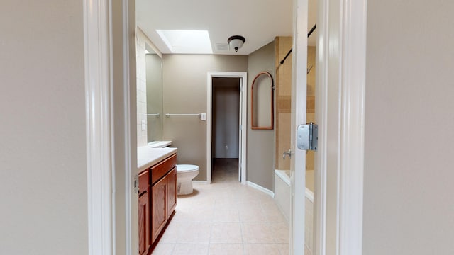 full bathroom featuring a skylight, tile patterned floors, toilet, vanity, and bathtub / shower combination