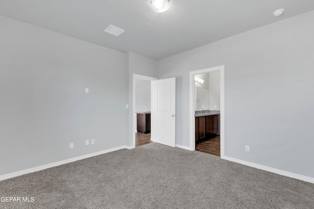 unfurnished bedroom featuring ensuite bath and carpet floors