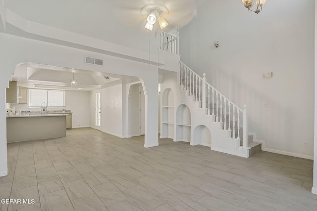 unfurnished living room with ceiling fan, a raised ceiling, and sink