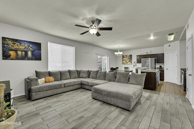 living room with ceiling fan with notable chandelier and sink