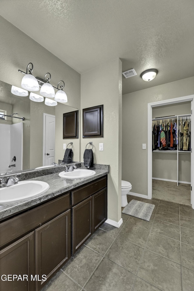 bathroom featuring vanity, a textured ceiling, toilet, and walk in shower