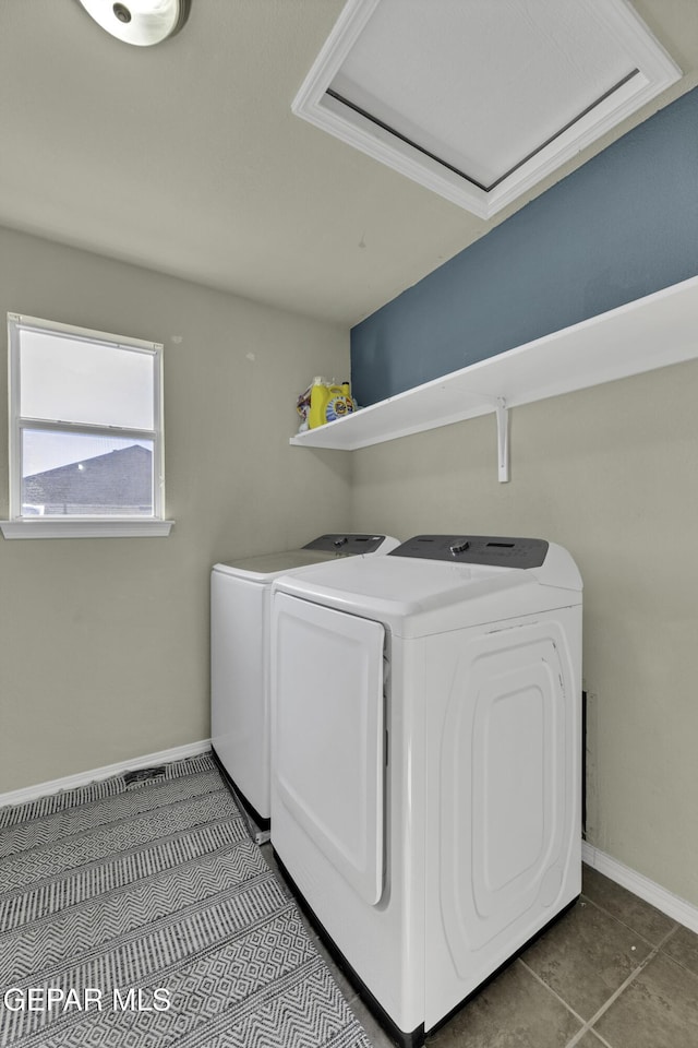 laundry room with dark tile patterned flooring and washing machine and clothes dryer