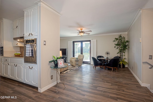 kitchen featuring ceiling fan, stainless steel oven, dark hardwood / wood-style floors, crown molding, and white cabinets