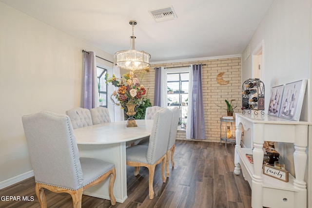 dining room featuring dark hardwood / wood-style flooring, brick wall, and a notable chandelier