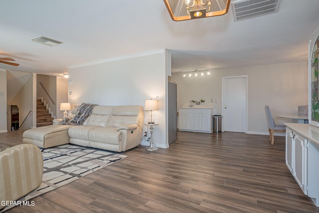 living room with ceiling fan with notable chandelier, dark hardwood / wood-style flooring, and crown molding