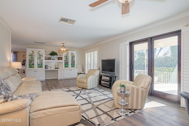 living room with ceiling fan, light wood-type flooring, and crown molding