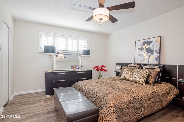 bedroom with a textured ceiling, light hardwood / wood-style flooring, and ceiling fan