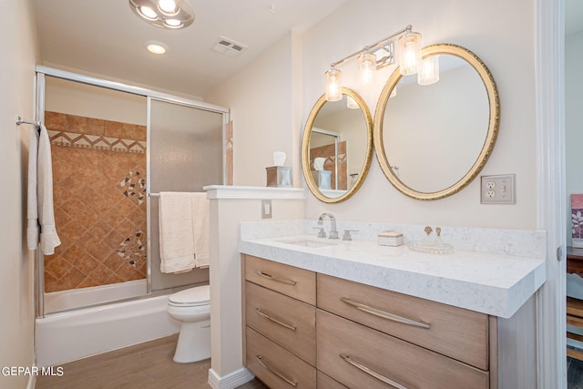 full bathroom with combined bath / shower with glass door, hardwood / wood-style floors, vanity, and toilet