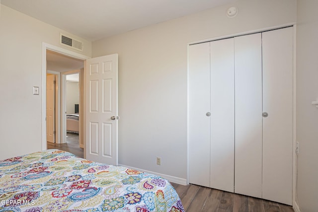 bedroom with dark hardwood / wood-style flooring and a closet