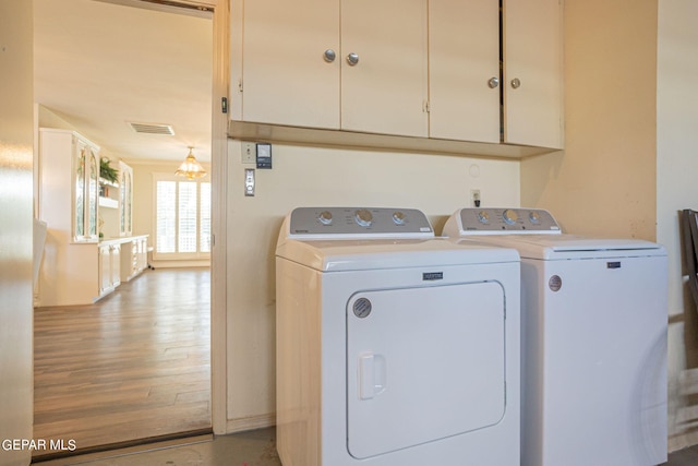 washroom featuring cabinets, light wood-type flooring, and washing machine and dryer