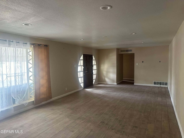 unfurnished room featuring wood-type flooring and a textured ceiling