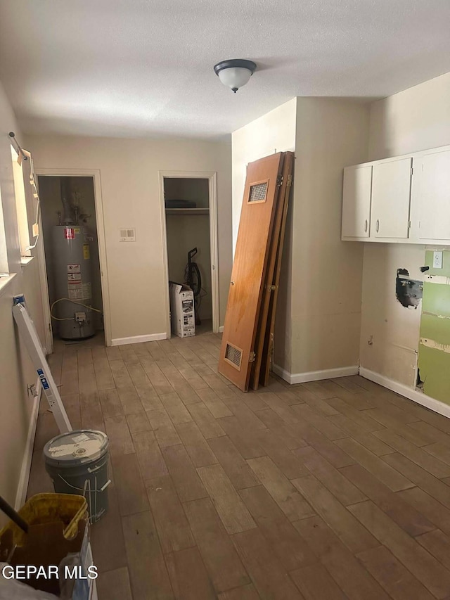 interior space featuring hardwood / wood-style flooring, gas water heater, and a textured ceiling