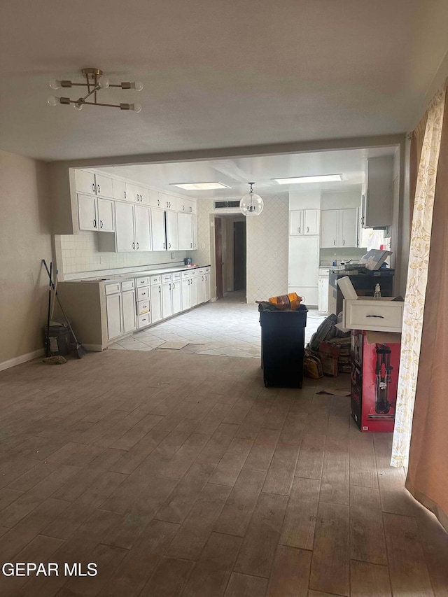 interior space with backsplash, hardwood / wood-style flooring, and white cabinetry