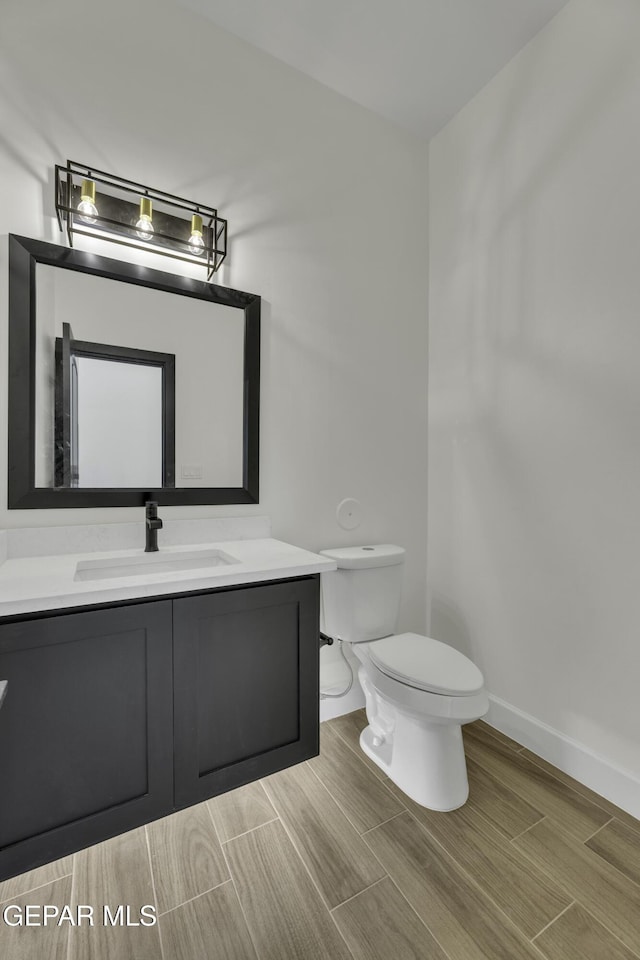 1762 Green Valley St, El Paso, TX 79928 - bathroom featuring vanity, toilet, baseboards, and wood finish floors