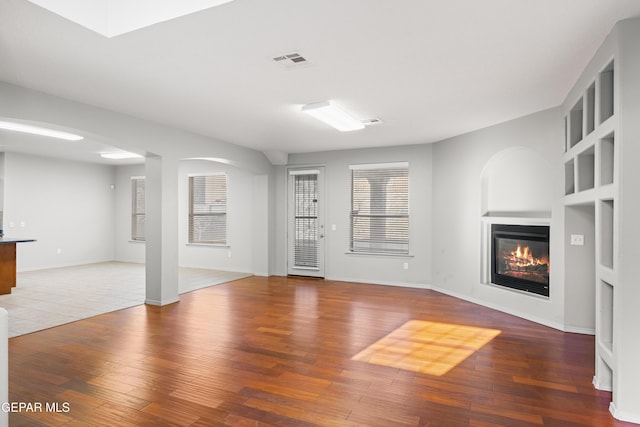 unfurnished living room featuring built in shelves and hardwood / wood-style floors