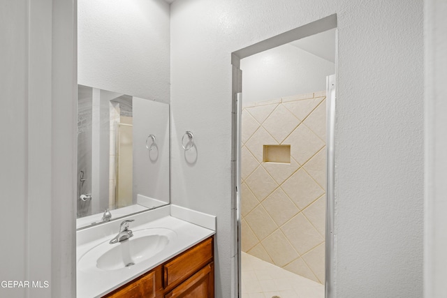 bathroom featuring a shower with door and vanity