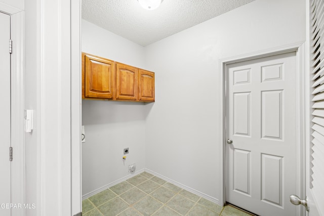 laundry area with electric dryer hookup, cabinets, and a textured ceiling