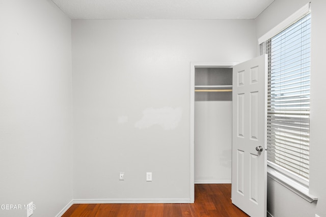 unfurnished bedroom with dark hardwood / wood-style floors and a closet