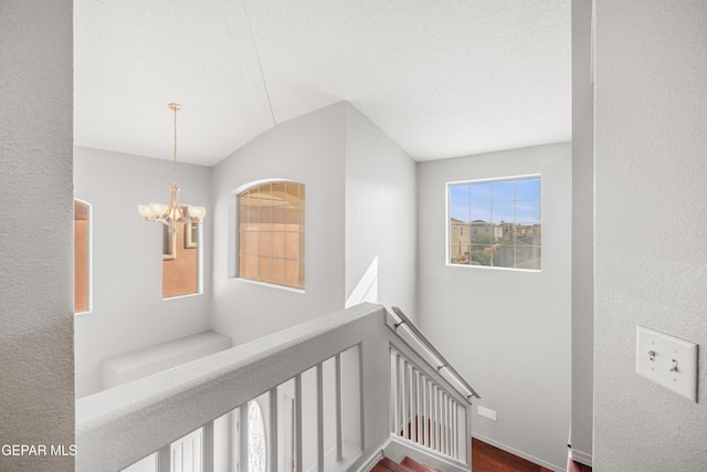 hallway featuring a textured ceiling and an inviting chandelier