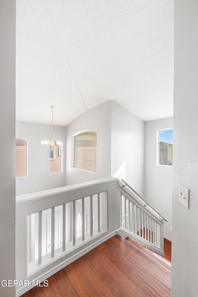 hall with a notable chandelier, hardwood / wood-style floors, and a textured ceiling