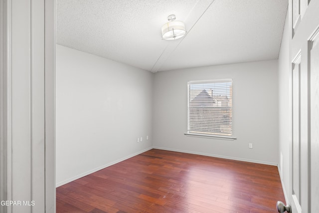 spare room with a textured ceiling and dark hardwood / wood-style flooring