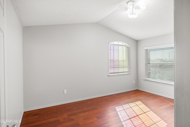 unfurnished room featuring wood-type flooring, a textured ceiling, and lofted ceiling