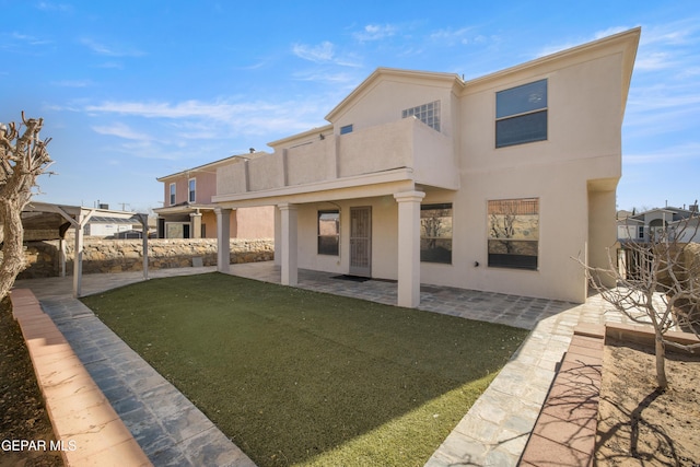 rear view of property with a balcony, a patio area, and a yard