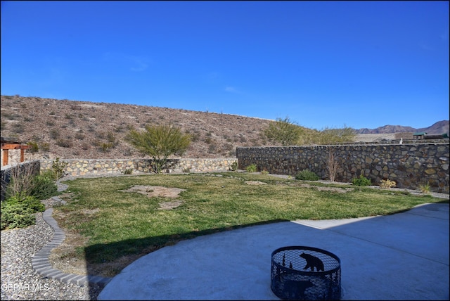 view of yard with a mountain view, a patio, and an outdoor fire pit