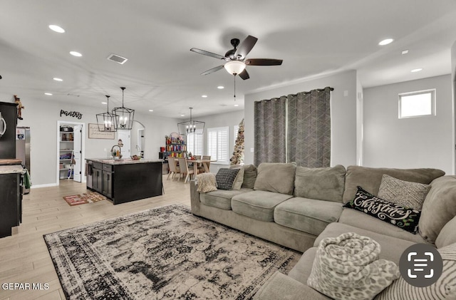 living room featuring sink, ceiling fan with notable chandelier, and light wood-type flooring