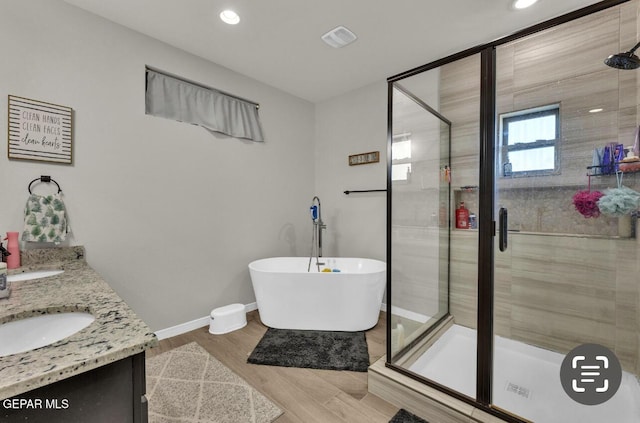 bathroom with hardwood / wood-style flooring, vanity, and plus walk in shower