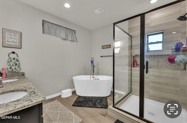 bathroom featuring vanity, hardwood / wood-style flooring, and plus walk in shower