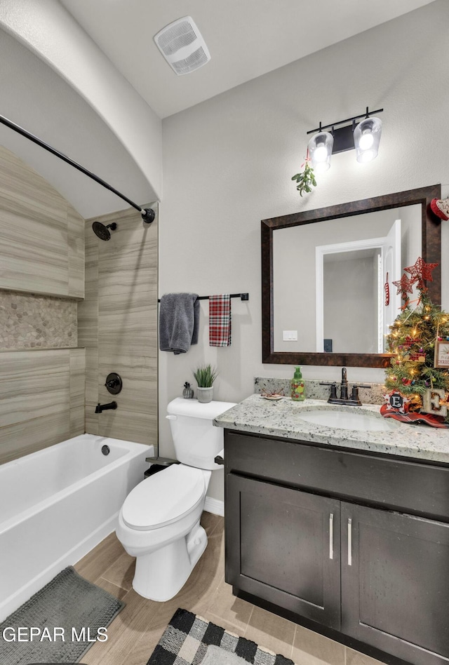 full bathroom with tiled shower / bath, vanity, and toilet