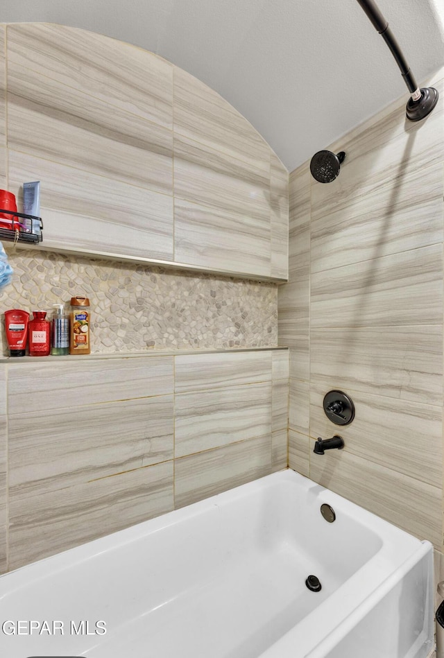 bathroom featuring tiled shower / bath combo and vaulted ceiling