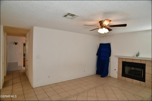 12560 Angie Bombach Ave, El Paso, TX 79928 - unfurnished living room with a tile fireplace, ceiling fan, light tile patterned floors, and a textured ceiling