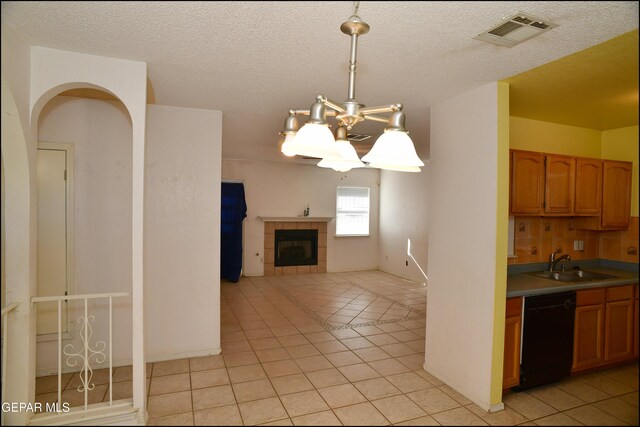 12560 Angie Bombach Ave, El Paso, TX 79928 - kitchen featuring light tile patterned flooring, decorative light fixtures, an inviting chandelier, dishwasher, and a tiled fireplace
