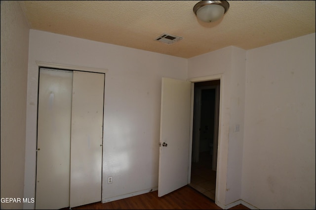 12560 Angie Bombach Ave, El Paso, TX 79928 - unfurnished bedroom with dark wood-type flooring, a textured ceiling, and a closet