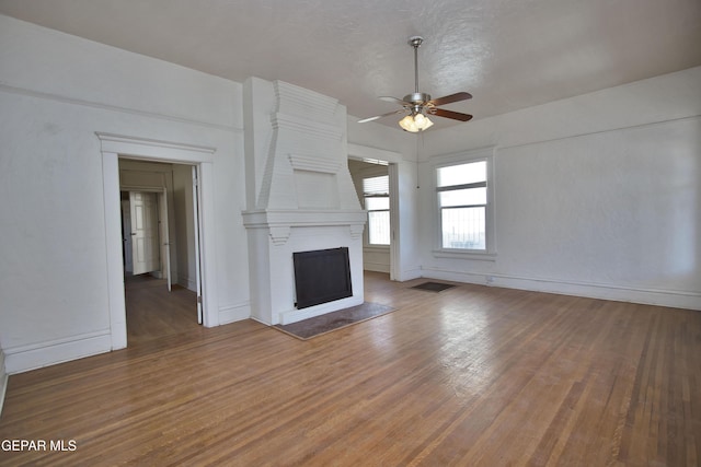 unfurnished living room with ceiling fan, a fireplace, and hardwood / wood-style flooring