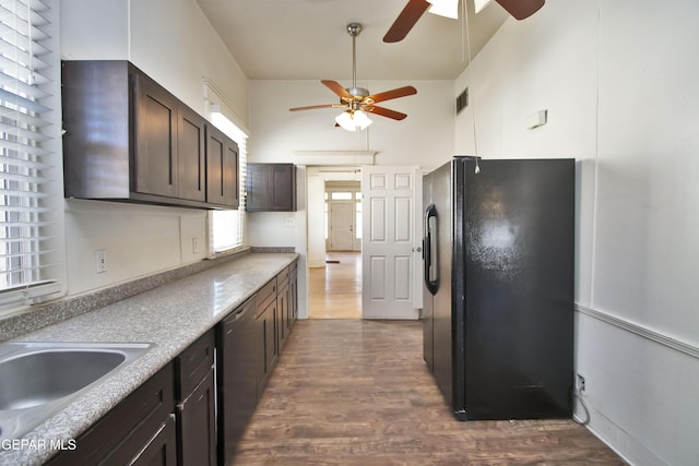 kitchen featuring black refrigerator, dark brown cabinets, dark wood-type flooring, sink, and dishwasher