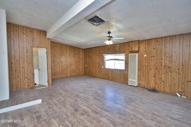 empty room featuring beamed ceiling, ceiling fan, a textured ceiling, and hardwood / wood-style flooring