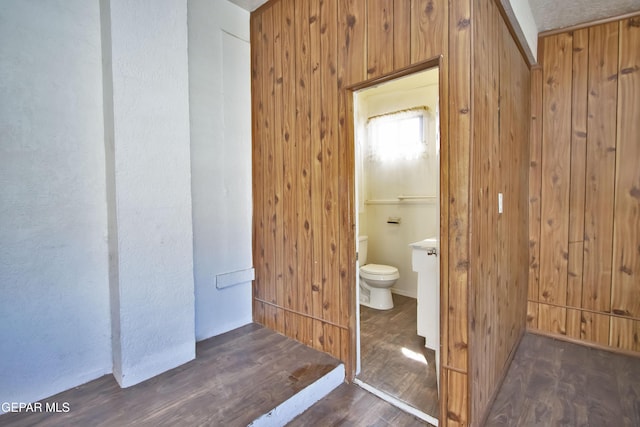 bathroom with hardwood / wood-style flooring, wood walls, and toilet