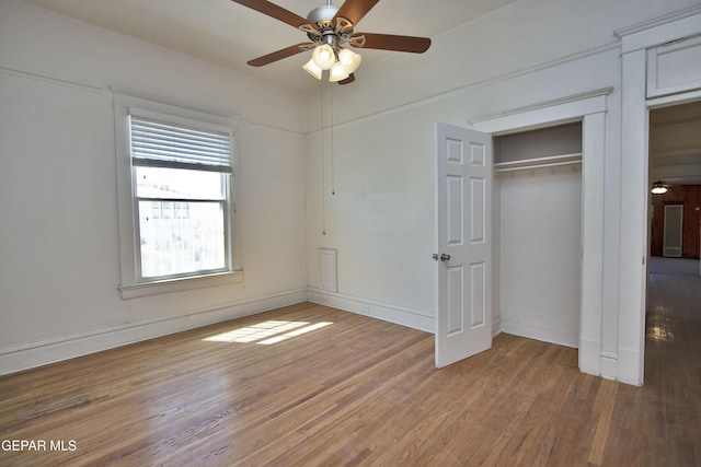 unfurnished bedroom featuring ceiling fan, a closet, and hardwood / wood-style flooring