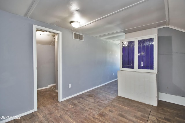 empty room with lofted ceiling and dark wood-type flooring