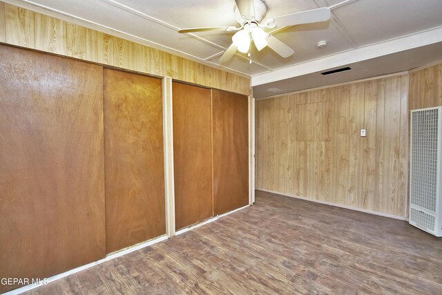 unfurnished room featuring wood walls, hardwood / wood-style floors, and ceiling fan