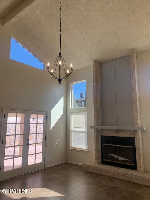 unfurnished living room with beamed ceiling, french doors, high vaulted ceiling, and a brick fireplace