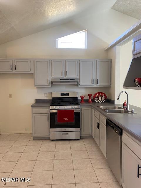 kitchen featuring gray cabinetry, lofted ceiling, sink, and appliances with stainless steel finishes