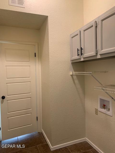 laundry area featuring hookup for a washing machine, dark tile patterned floors, and cabinets