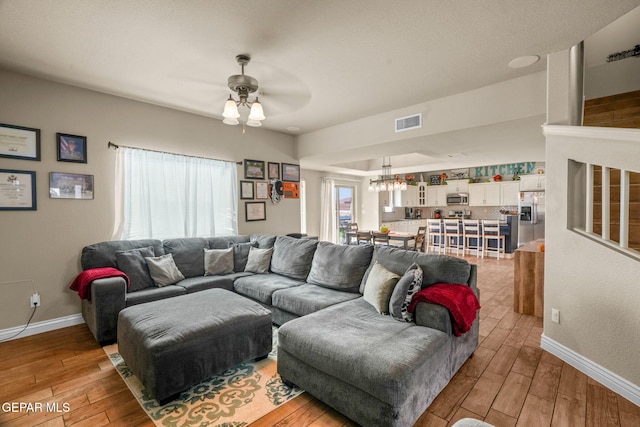 living room featuring ceiling fan with notable chandelier