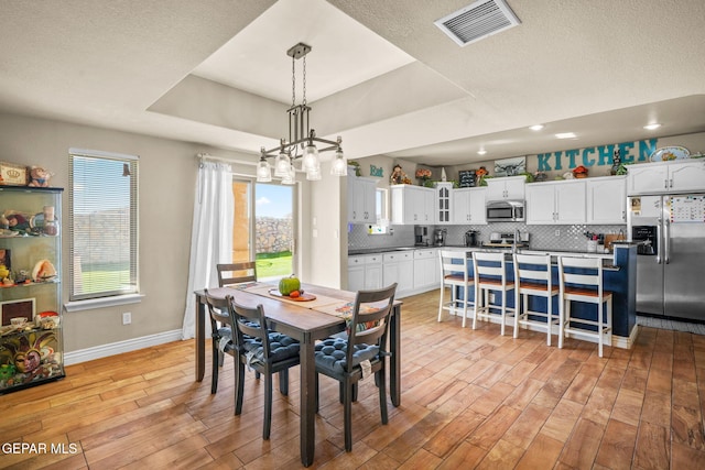 dining space featuring light hardwood / wood-style floors and a raised ceiling