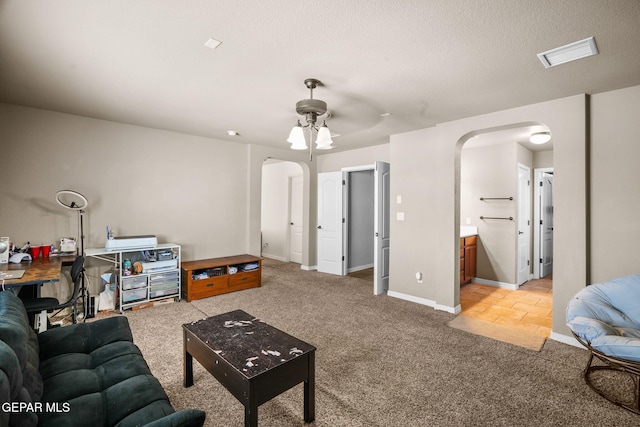 living room featuring a textured ceiling, ceiling fan, and light carpet