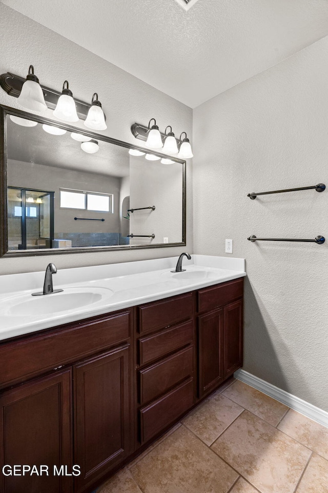 bathroom with tile patterned flooring, a textured ceiling, and vanity